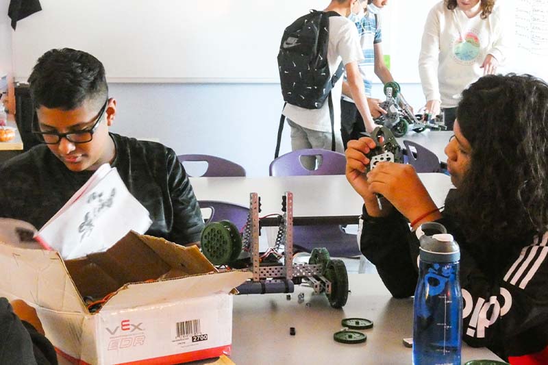 Students building robot with kit