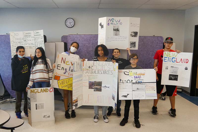 Students holding New England project posters
